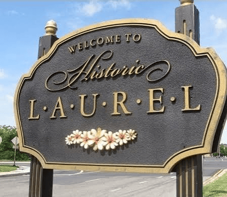 Welcome sign for Historic Laurel, featuring ornate lettering and floral decorations.