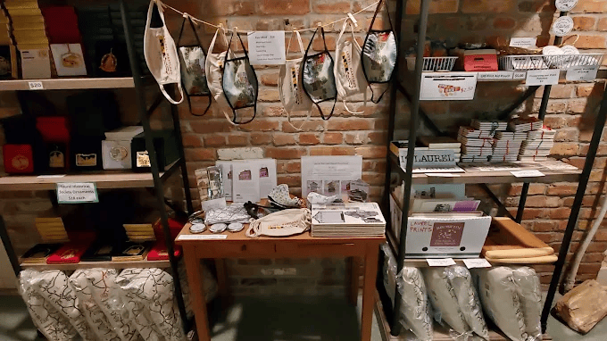 A display of various retail items including decorative face masks, books, and stationery on shelves against a brick wall.